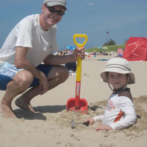 Tom next to Theodore buried in sand at the beach