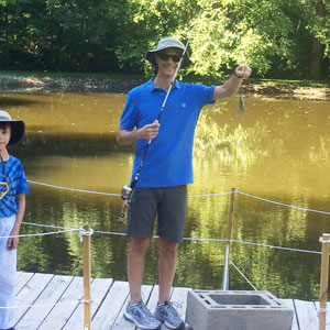 Tom on pier holding up small fish